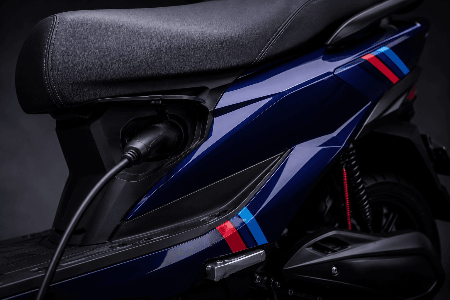 Close-up of an electric scooter's charging port with the cable plugged in